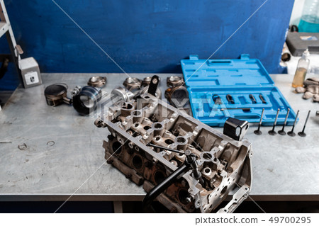 Disassembled engine block is on the table. the mechanic opened the locking valve mechanism. Motor Disassembled engine block is on the table. the mechanic opened the locking valve mechanism. Motor 49700295
