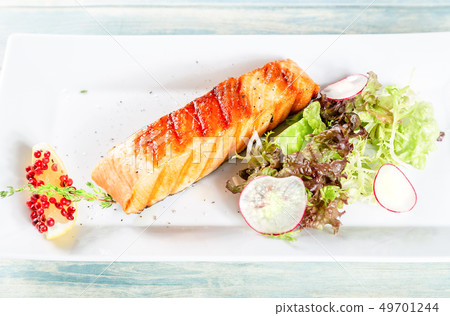 Grilled salmon with lettuce, redish and lemon 49701244