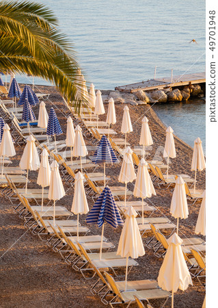 Summer sunrise on coast, Corfu island, Greece. Beach with Sunbeds and umbrellas with perfect views Summer sunrise on coast, Corfu island, Greece. Beach with Sunbeds and umbrellas with perfect views 49701948