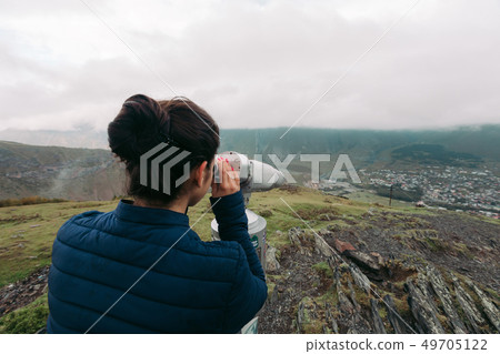 tourist woman looking at binoculars on a hillside tourist woman looking at binoculars on a hillside 49705122