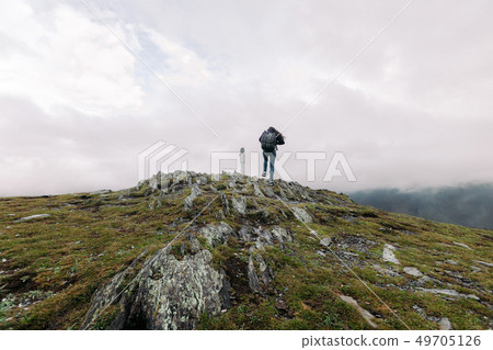 woman climbs to the binoculars on a hillside woman climbs to the binoculars on a hillside 49705126