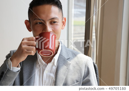 Businessman looking out of the window drinking coffee 49705180