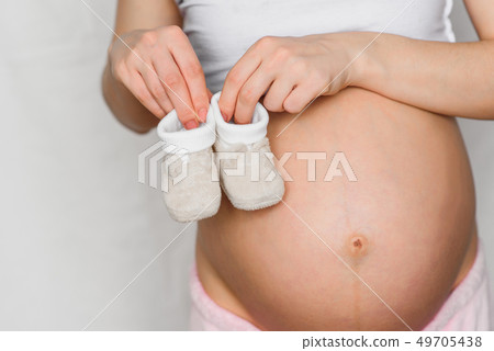 booties for newborn in the hands of a pregnant girl booties for newborn in the hands of a pregnant girl 49705438
