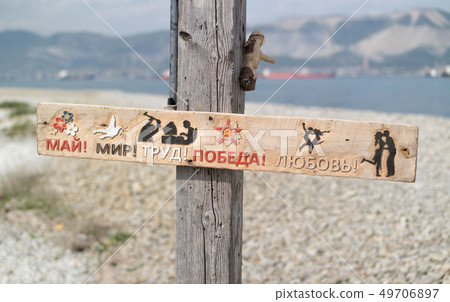 Wooden signboard in Russian on the background of the sea: May, Peace, Work, Victory, Love 49706897