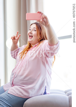 Positive happy plump woman posing for a selfie Positive happy plump woman posing for a selfie 49707851