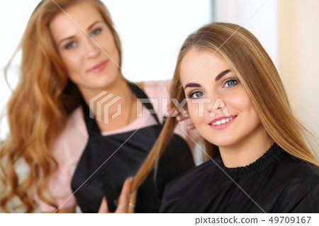 Beautiful blonde female hairdresser holding lock of hair 49709167