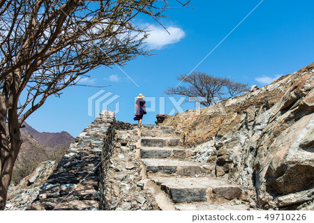 Woman climbing stairs to desert fortress Woman climbing stairs to desert fortress 49710226