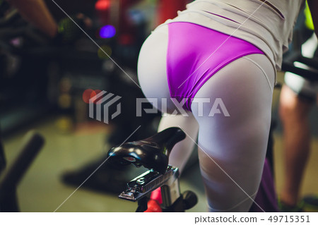 Beautiful young woman in a gym female on bicycle. fanny 49715351