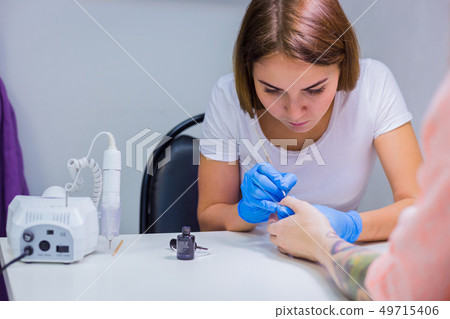 Professional beautician applying nail polish to female nail Professional beautician applying nail polish to female nail 49715406