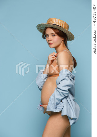 Young beautiful pregnant woman posing on blue background Young beautiful pregnant woman posing on blue background 49715407