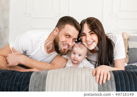 Happy smiling young family portrait in bedroom. Happy smiling young family portrait in bedroom. 49716149