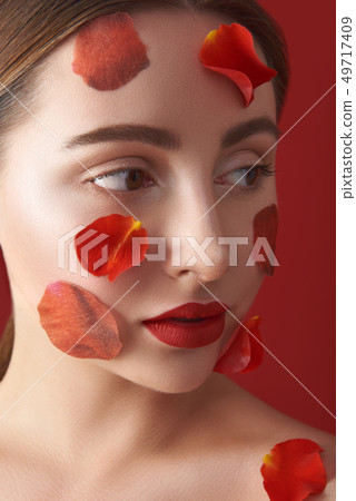 Woman with rose petals turning her face to the left 49717409