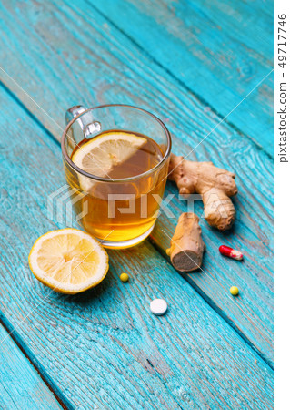 Cold medicines, tea, lemon and ginger on wooden blue background Cold medicines, tea, lemon and ginger on wooden blue background 49717746