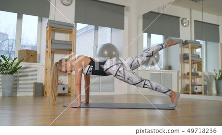 the girl shows the Pilates exercise. Pilates in the sports hall. the girl is engaged in pilates. The the girl shows the Pilates exercise. Pilates in the sports hall. the girl is engaged in pilates. The 49718236