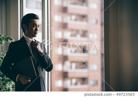 站立與文件的上司人在窗口旁邊 站立與文件的上司人在窗口旁邊 49723563