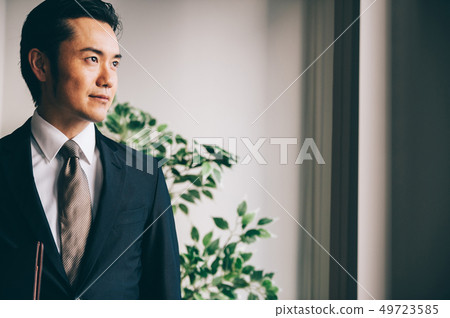 Boss man standing with files by the window 49723585
