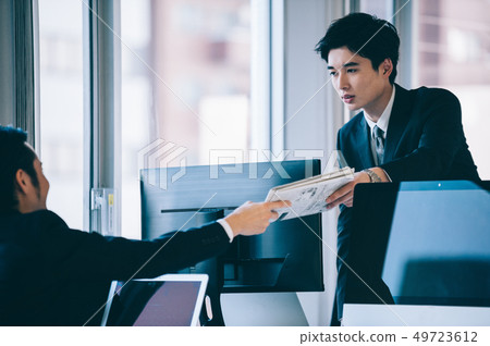 Boss and subordinate men handing materials over the desk 49723612