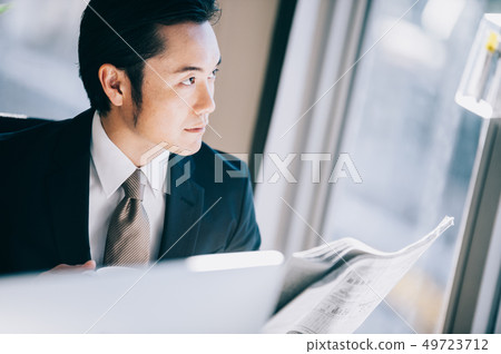 讀一張報紙的上司人，當朝向在窗口的一個位子的個人計算機時 49723712