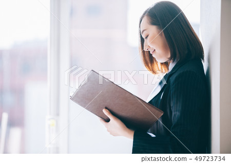 Woman checking file leaning on pillar at office 49723734