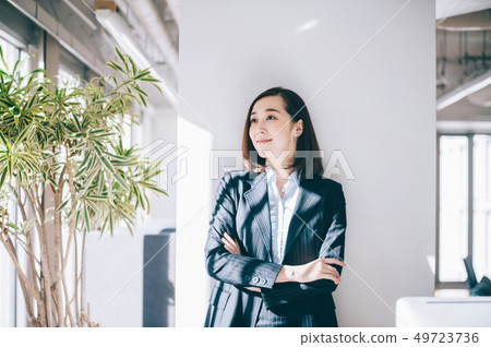 Smiling woman leaning on pillar at office 49723736