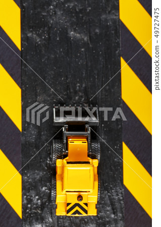 Yellow toy bulldozer on a black background Yellow toy bulldozer on a black background 49727475