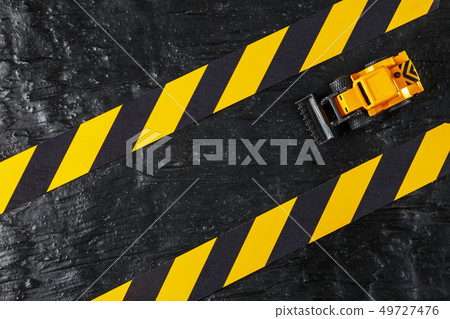 Yellow toy bulldozer on a black background Yellow toy bulldozer on a black background 49727476