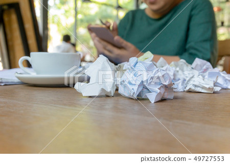 Wwoman hand using cell phone working after hours with crumpled paper on table. 49727553