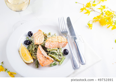 Grilled salmon with steamed green beans and lemon on white background with white wine Grilled salmon with steamed green beans and lemon on white background with white wine 49732891