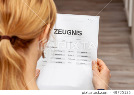 Mother holding a very bad German school certificate in her hands Translation: certificate day of 49735125
