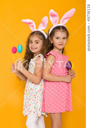 little girls with Easter bunny ears holding colorful eggs 49736116