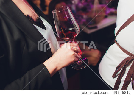 Glass of wine in beautiful female hands. Large glass filled with red wine in woman manicured hands 49736812