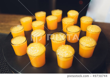17 alcoholic drink in shot glasses with orange slices in the wood table. 17 alcoholic drink in shot glasses with orange slices in the wood table. 49738744