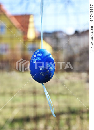 Painted egg hangs in a garden at easter holiday. Painted egg hangs in a garden at easter holiday. 49745457