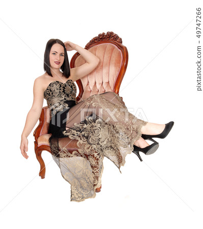 Beautiful woman sitting in armchair, legs over the Beautiful woman sitting in armchair, legs over the 49747266