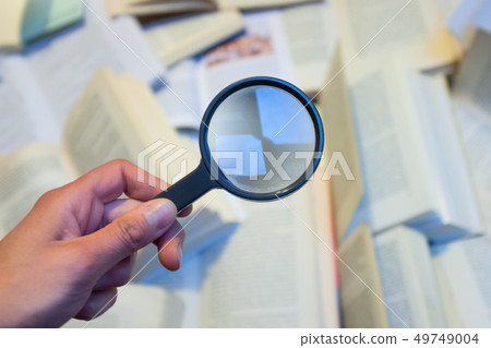 Magnifying glass to check various books Magnifying glass to check various books 49749004