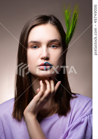 Blue-eyed model with blue lines on her lips posing with spikelet Blue-eyed model with blue lines on her lips posing with spikelet 49749006