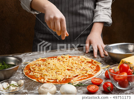 Preparing pizza. Woman adding cheese to pizza Preparing pizza. Woman adding cheese to pizza 49751173