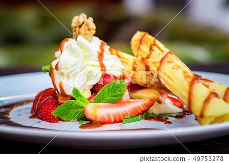 Close up delicious dessert with waffle rolls, ice cream and strawberries 49753278