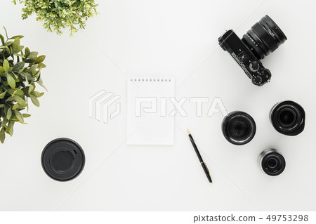 Mocap work photographer on a white table. Flat lay mirrorless camera, a few lenses and a notebook 49753298