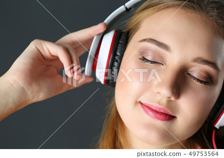 Beautiful blonde smiling woman with eyes closed wearing headphones Beautiful blonde smiling woman with eyes closed wearing headphones 49753564