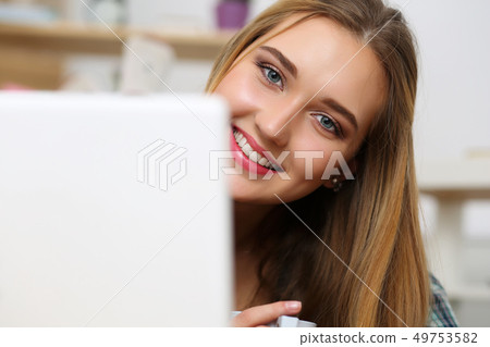Beautiful blonde smiling woman lying on floor with laptop computer Beautiful blonde smiling woman lying on floor with laptop computer 49753582