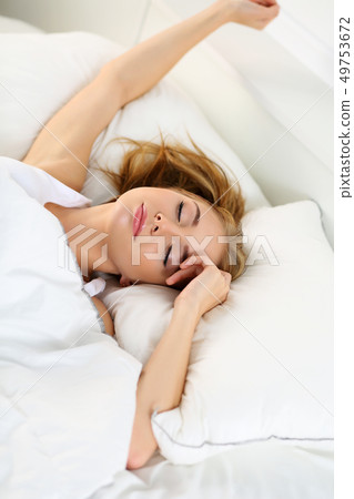 Young beautiful blonde woman lying in bed trying to wake up 49753672