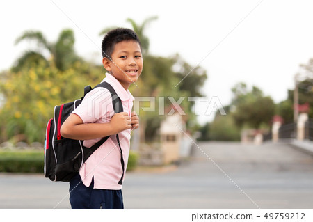 Happy asian school boy in uniform with backpack walking back home. Happy asian school boy in uniform with backpack walking back home. 49759212