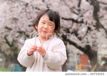 Girl making a heart symbol against a background of cherry blossoms 49759565