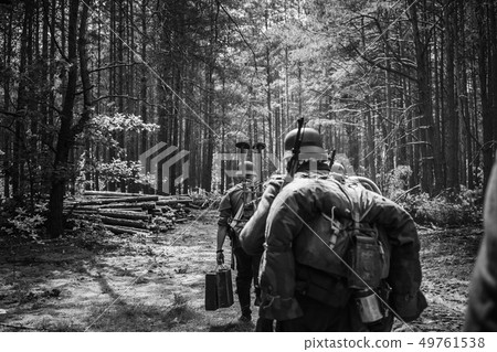 Re-enactors Dressed As German Infantry Soldiers In World War II Marching Walking Along Forest Road 49761538