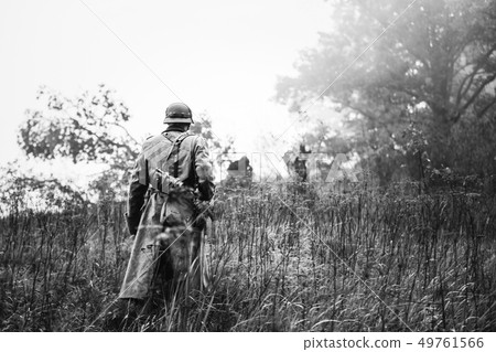 Single Re-enactor Dressed As German Wehrmacht Infantry Soldier In World War II Walking In Patrol 49761566