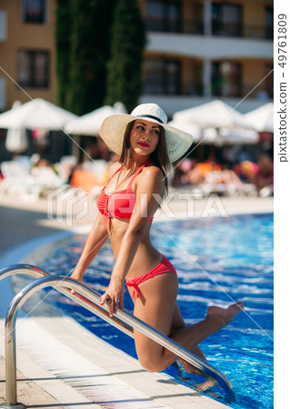 A Sexy lady in a big beach hat get out of the swimming pool 49761809