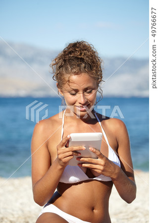 Woman with an e-reader on vacation at the beach Woman with an e-reader on vacation at the beach 49766677