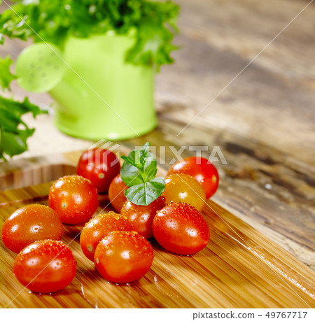 Cherry tomatoes with basil on a wood table Cherry tomatoes with basil on a wood table 49767717