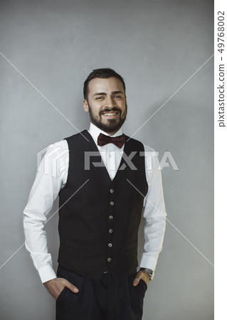 Smiling man in black vest and bow tie 49768002